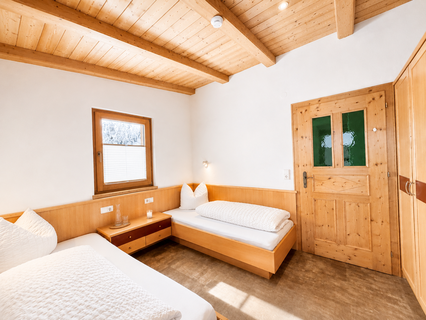 Gemütliches Apartmentzimmer mit zwei Holzbetten, Holzdecke und grüner Tür - Das Auss.Zeit Apartment