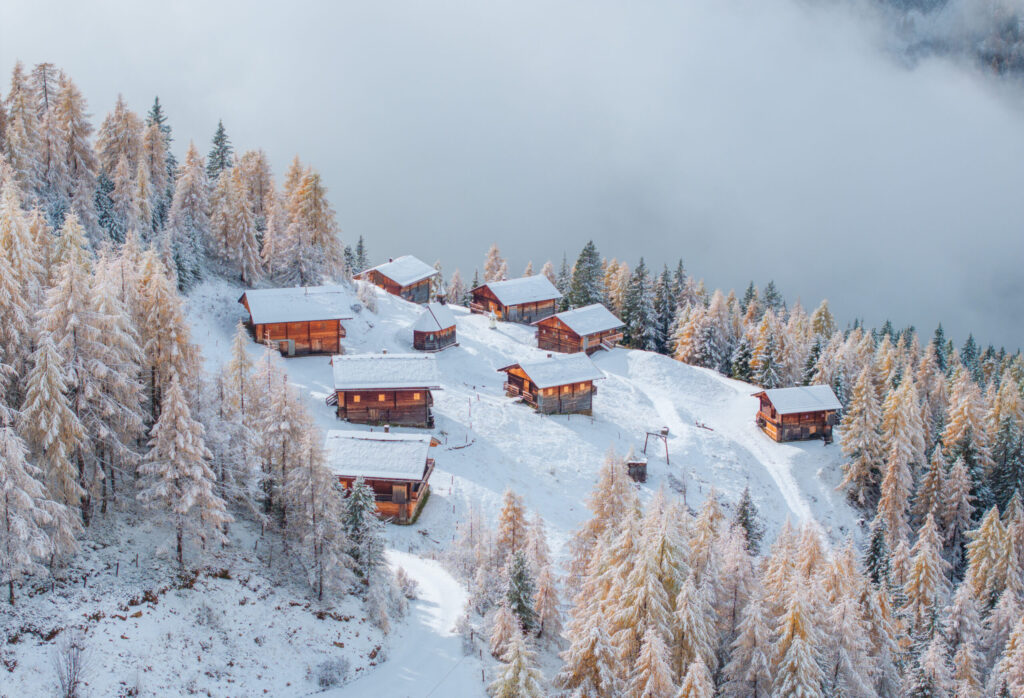 default Verschneite Berghütten und Skilifte inmitten von schneebedeckten Lärchen und Fichtenwäldern in einem alpinen Wintersportort